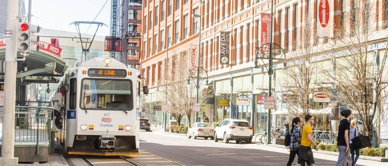 This is a color photograph of public transportation, the RTD Light Rail Tram on the tracks in urban, downtown Denver, Colorado a Western USA city. Photographed with a Nikon D800 on an unusually warm winter day.