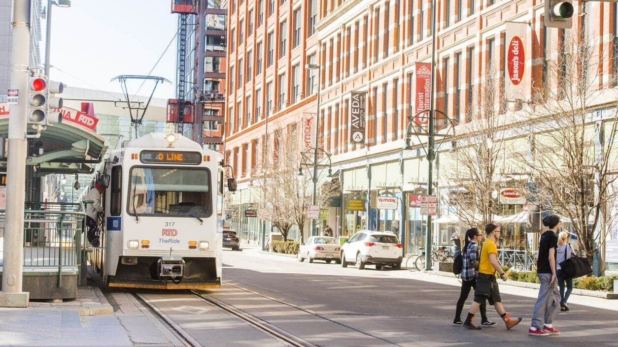 This is a color photograph of public transportation, the RTD Light Rail Tram on the tracks in urban, downtown Denver, Colorado a Western USA city. Photographed with a Nikon D800 on an unusually warm winter day.