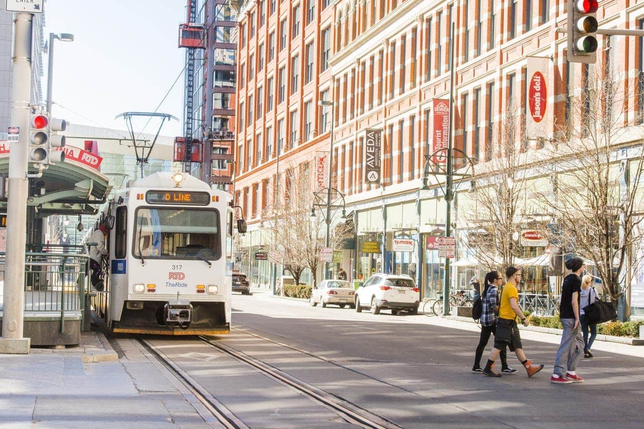 This is a color photograph of public transportation, the RTD Light Rail Tram on the tracks in urban, downtown Denver, Colorado a Western USA city. Photographed with a Nikon D800 on an unusually warm winter day.