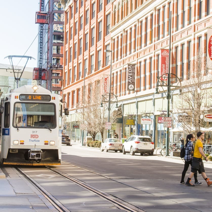 This is a color photograph of public transportation, the RTD Light Rail Tram on the tracks in urban, downtown Denver, Colorado a Western USA city. Photographed with a Nikon D800 on an unusually warm winter day.