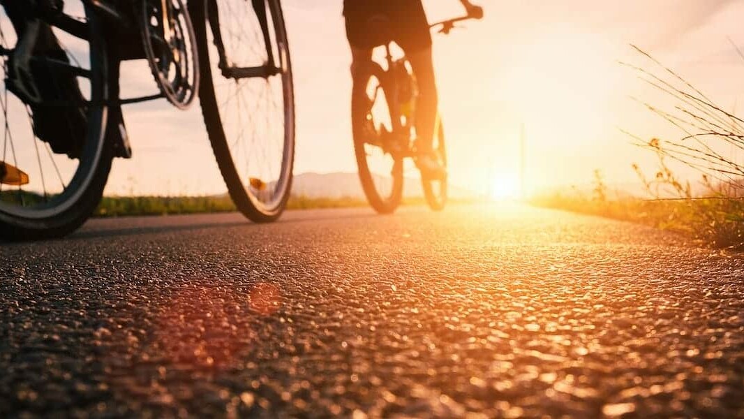 Bike wheels close up image on asphalt sunset road